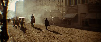 Movie still from “The Assassination of Jesse James by the Coward Robert Ford” (2007), directed by Andrew Dominik – A man in a top hat is walking on a cobblestone street; Wide shot, High angle
