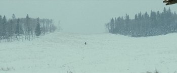 Movie still from “The Assassination of Jesse James by the Coward Robert Ford” (2007), directed by Andrew Dominik – A person riding a snowboard down a snow covered slope; Extreme Wide shot, High angle