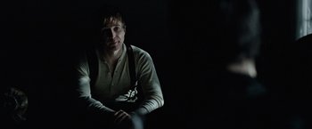 Movie still from “The Assassination of Jesse James by the Coward Robert Ford” (2007), directed by Andrew Dominik – A man sitting in a dark room with a dark background; Close Up shot, Over the shoulder angle