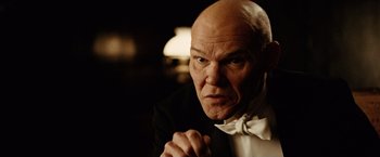 Movie still from “The Assassination of Jesse James by the Coward Robert Ford” (2007), directed by Andrew Dominik – A bald man in a black suit and white bow tie; Close Up shot, Low angle