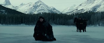 Movie still from “The Assassination of Jesse James by the Coward Robert Ford” (2007), directed by Andrew Dominik – A man sitting in the middle of a snowy field with mountains in the background; Wide shot, Low angle