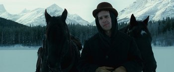 Movie still from “The Assassination of Jesse James by the Coward Robert Ford” (2007), directed by Andrew Dominik – A man wearing a hat sitting next to a horse in the snow; Close Up shot, Low angle