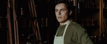 Movie still from “The Assassination of Jesse James by the Coward Robert Ford” (2007), directed by Andrew Dominik – A man wearing an apron standing next to a ladder; Close Up shot, Low angle