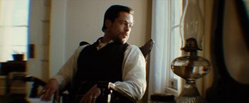 Movie still from “The Assassination of Jesse James by the Coward Robert Ford” (2007), directed by Andrew Dominik – A man sitting in a chair looking out a window; Medium shot, Low angle
