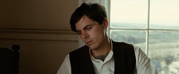 Movie still from “The Assassination of Jesse James by the Coward Robert Ford” (2007), directed by Andrew Dominik – A young man in a white shirt and black vest looking down; Close Up shot, Low angle