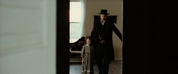 Movie still from “The Assassination of Jesse James by the Coward Robert Ford” (2007), directed by Andrew Dominik – A man and a little girl dressed up in costumes; Medium shot, Over the shoulder angle