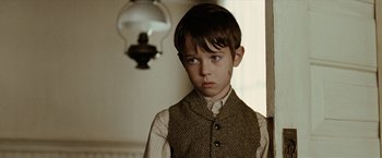 Movie still from “The Assassination of Jesse James by the Coward Robert Ford” (2007), directed by Andrew Dominik – A young boy wearing a vest and a tie; Close Up shot, Over the shoulder angle