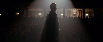 Movie still from “The Assassination of Jesse James by the Coward Robert Ford” (2007), directed by Andrew Dominik – A man standing in front of an audience at a concert; Wide shot, Low angle
