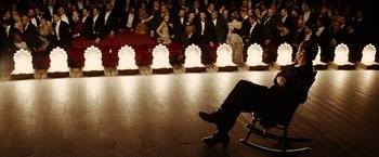Movie still from “The Assassination of Jesse James by the Coward Robert Ford” (2007), directed by Andrew Dominik – A man sitting on a chair in front of a crowd of people; Wide shot, High angle