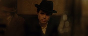 Movie still from “The Assassination of Jesse James by the Coward Robert Ford” (2007), directed by Andrew Dominik – A man wearing a black hat sitting in a room; Close Up shot, Over the shoulder angle