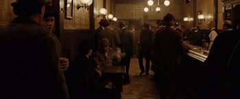 Movie still from “The Assassination of Jesse James by the Coward Robert Ford” (2007), directed by Andrew Dominik – A group of men standing around a room; Wide shot, High angle