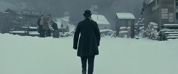 Movie still from “The Assassination of Jesse James by the Coward Robert Ford” (2007), directed by Andrew Dominik – A man in a black coat and hat walking in the snow; Wide shot, Over the shoulder angle