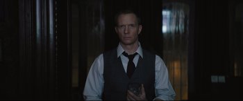 Movie still from “The Batman” (2022), directed by Matt Reeves – A man in a vest and tie holding a rock; Medium shot, Over the shoulder angle