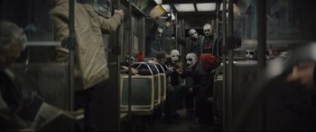 Movie still from “The Batman” (2022), directed by Matt Reeves – A group of people in masks riding on a subway train; Wide shot, High angle