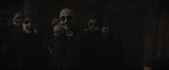 Movie still from “The Batman” (2022), directed by Matt Reeves – A group of people with faces painted in a dark room; Medium shot, Over the shoulder angle