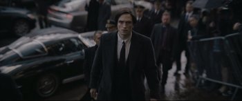 Movie still from “The Batman” (2022), directed by Matt Reeves – A man in a suit and tie walking down a street; Medium shot, Over the shoulder angle
