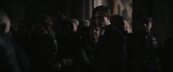 Movie still from “The Batman” (2022), directed by Matt Reeves – A man standing in front of a group of people; Medium shot, Over the shoulder angle