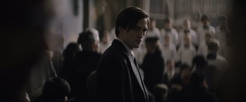 Movie still from “The Batman” (2022), directed by Matt Reeves – A man in a suit standing in front of a group of people; Close Up shot, Over the shoulder angle