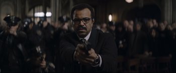 Movie still from “The Batman” (2022), directed by Matt Reeves – A man in a suit and tie holding a gun; Close Up shot, Low angle