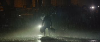 Movie still from “The Batman” (2022), directed by Matt Reeves – A man walking in the rain with a bag of luggage; Extreme Wide shot, Low angle