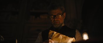 Movie still from “The Batman” (2022), directed by Matt Reeves – An older man looking at a piece of paper in a dimly - lit room; Close Up shot, Over the shoulder angle