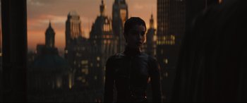 Movie still from “The Batman” (2022), directed by Matt Reeves – A woman standing in front of a city skyline at night; Medium shot, Over the shoulder angle