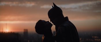 Movie still from “The Batman” (2022), directed by Matt Reeves – A man and a woman kissing in front of a city skyline; Medium shot, Low angle