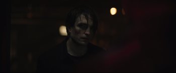 Movie still from “The Batman” (2022), directed by Matt Reeves – A man with wet hair is standing in the dark; Close Up shot, Over the shoulder angle