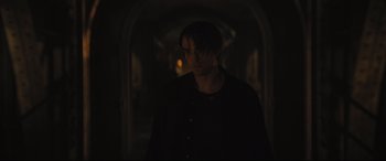 Movie still from “The Batman” (2022), directed by Matt Reeves – A man in a black shirt standing in a dark room; Medium shot, Over the shoulder angle