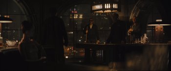Movie still from “The Batman” (2022), directed by Matt Reeves – A group of people standing around a table with a pool stick; Wide shot, Over the shoulder angle
