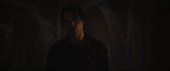 Movie still from “The Batman” (2022), directed by Matt Reeves – A man with long hair and glasses in a dark room; Close Up shot, Over the shoulder angle