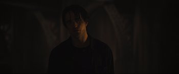 Movie still from “The Batman” (2022), directed by Matt Reeves – A young man in a dark room with dark lighting; Medium shot, Over the shoulder angle