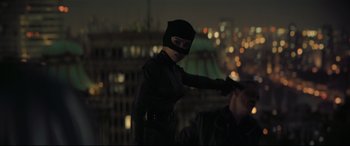Movie still from “The Batman” (2022), directed by Matt Reeves – A woman dressed as a catwoman is standing in front of a city skyline at night; Medium shot, Over the shoulder angle
