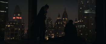 Movie still from “The Batman” (2022), directed by Matt Reeves – Two people dressed up as batman and robin in front of a city skyline at night; Wide shot, Low angle
