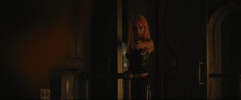 Movie still from “The Batman” (2022), directed by Matt Reeves – A woman in a black outfit is holding a gun; Medium shot, Over the shoulder angle