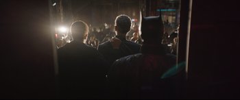 Movie still from “The Batman” (2022), directed by Matt Reeves – A group of people standing in front of a crowd; Medium shot, Over the shoulder angle