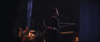 Movie still from “The Batman” (2022), directed by Matt Reeves – A woman standing at a podium speaking to a crowd of onlookers; Medium shot, Low angle