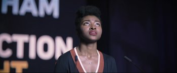 Movie still from “The Batman” (2022), directed by Matt Reeves – A woman looking up into the air with a necklace hanging from her neck; Close Up shot, Low angle