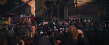 Movie still from “The Batman” (2022), directed by Matt Reeves – A group of people standing around a crowd of people; Medium shot, Over the shoulder angle
