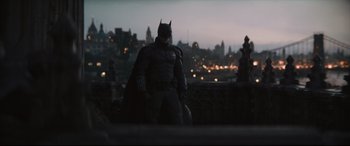 Movie still from “The Batman” (2022), directed by Matt Reeves – A man dressed as batman standing in front of a city skyline; Wide shot, Over the shoulder angle