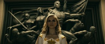 Movie still from “The Boys” (2019), created by Eric Kripke – A woman standing in front of a statue of a man and a woman; Medium shot, Low angle