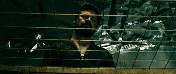 Movie still from “The Boys” (2019), created by Eric Kripke – A man looking out of a window through a fence; Medium shot, Low angle