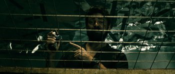 Movie still from “The Boys” (2019), created by Eric Kripke – A bearded man is looking through a fence; Close Up shot, Low angle