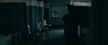 Movie still from “The Boys” (2019), created by Eric Kripke – A person standing in a room with chairs in front of them; Extreme Wide shot, High angle