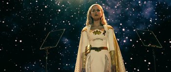 Movie still from “The Boys” (2019), created by Eric Kripke – A woman dressed in a white and gold costume stands in front of a star filled sky; Medium shot, Low angle