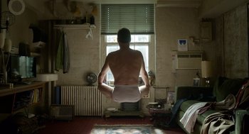 Movie still from “Birdman or (The Unexpected Virtue of Ignorance)” (2014), directed by Alejandro G. Iñárritu – A man sitting in front of a window in his underwear; Wide shot, Low angle