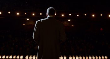 Movie still from “Birdman or (The Unexpected Virtue of Ignorance)” (2014), directed by Alejandro G. Iñárritu – A man standing in front of an audience on a stage; Wide shot, Over the shoulder angle