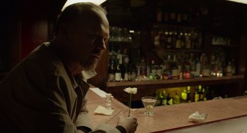 Movie still from “Birdman or (The Unexpected Virtue of Ignorance)” (2014), directed by Alejandro G. Iñárritu – An older man sitting at a bar with a flower in his hand; Medium shot, Over the shoulder angle