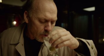 Movie still from “Birdman or (The Unexpected Virtue of Ignorance)” (2014), directed by Alejandro G. Iñárritu – An older man is drinking a glass of wine; Close Up shot, Low angle