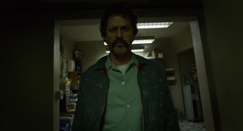 Movie still from “Birdman or (The Unexpected Virtue of Ignorance)” (2014), directed by Alejandro G. Iñárritu – A man in a green shirt is standing in a dark room; Medium shot, Low angle